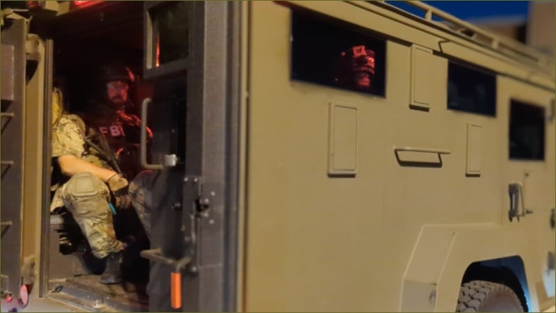 FBI SWAT operator in tactical gear sits ready to deploy from armored vehicle at night