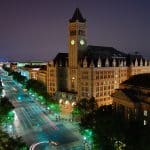 Old Post Office Pavilion and its clock tower illuminated at night on Pennsylvania Avenue in Washington DC with the US Capitol visible in the distance