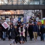 Hundreds of anti-ICE protesters march through downtown Minneapolis carrying signs reading "No One Likes You," "ICE Go Home," and "Resist" during winter demonstrations against federal immigration enforcement operations.