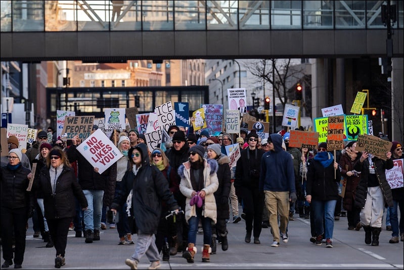 Hundreds of anti-ICE protesters march through downtown Minneapolis carrying signs reading "No One Likes You," "ICE Go Home," and "Resist" during winter demonstrations against federal immigration enforcement operations.