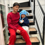 Five-year-old Liam Conejo Ramos wearing a blue hat sits on stairs with his father Adrian at their Minnesota home after release from ICE detention