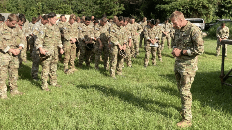 U.S. Army chaplain leads soldiers in prayer on a grassy field before a parachute jump at Fort Benning, Georgia, September 2023