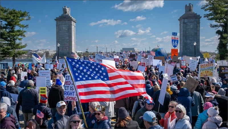 No Kings protesters fill Arlington Memorial Bridge carrying American flags and signs on March 28, 2026
