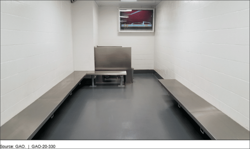 DHS immigration holding room with metal benches and no beds at a port of entry, photographed by the Government Accountability Office