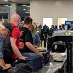 Travelers place luggage on the conveyor belt at a TSA security checkpoint at Long Beach Airport in California