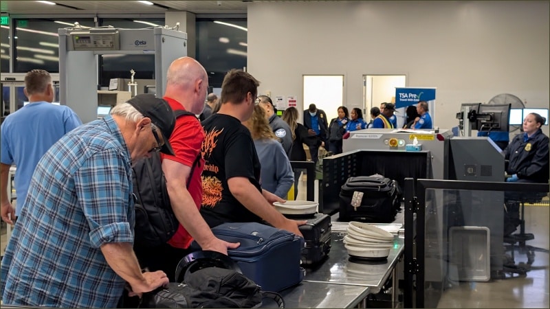 Travelers place luggage on the conveyor belt at a TSA security checkpoint at Long Beach Airport in California