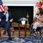Sen. Tammy Duckworth laughing in her wheelchair next to Maryland Gov. Wes Moore in the Governor's Reception Room in Annapolis