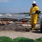 BP cleanup workers in yellow hazmat suits remove oil from Port Fourchon beach during 2010 Deepwater Horizon spill cleanup