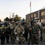 Border Patrol and ICE agents in tactical gear and face coverings massed outside the Broadview ICE detention facility near Chicago