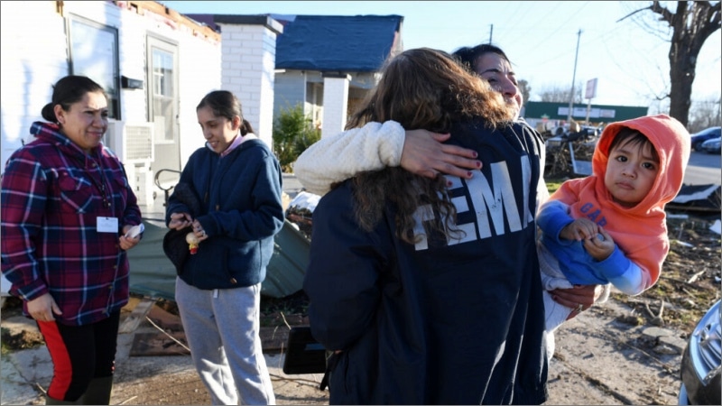 FEMA housing inspector hugging tornado survivor outside damaged home in Mayfield, Kentucky