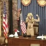 Jacob Chansley, the QAnon Shaman, in horned headdress raises fist at the Senate dais during the January 6, 2021 Capitol attack