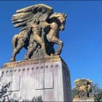 Gilded Arts of Peace equestrian sculptures at the Arlington Memorial Bridge gateway under a clear blue sky