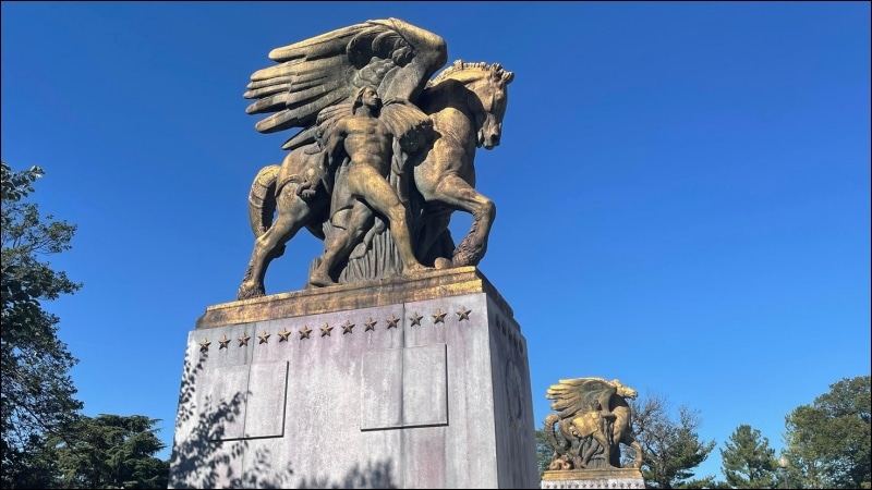 Gilded Arts of Peace equestrian sculptures at the Arlington Memorial Bridge gateway under a clear blue sky