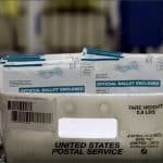 Tray of official mail-in ballot envelopes moving along a U.S. Postal Service sorting line