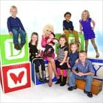 Dolly Parton seated among young children on oversized alphabet blocks promoting the Imagination Library free book program