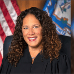Judge Melanie Cradle in her official portrait, wearing black judicial robes before the American and Connecticut state flags
