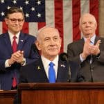 Benjamin Netanyahu speaks at the House rostrum with Speaker Mike Johnson and Senator Ben Cardin applauding behind him