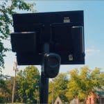 Flock Safety automated license plate reader camera and solar panel mounted on a pole in a residential neighborhood