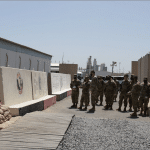 Soldiers stand between concrete blast walls and prefabricated buildings at Port Shuaiba, Kuwait, in 2021