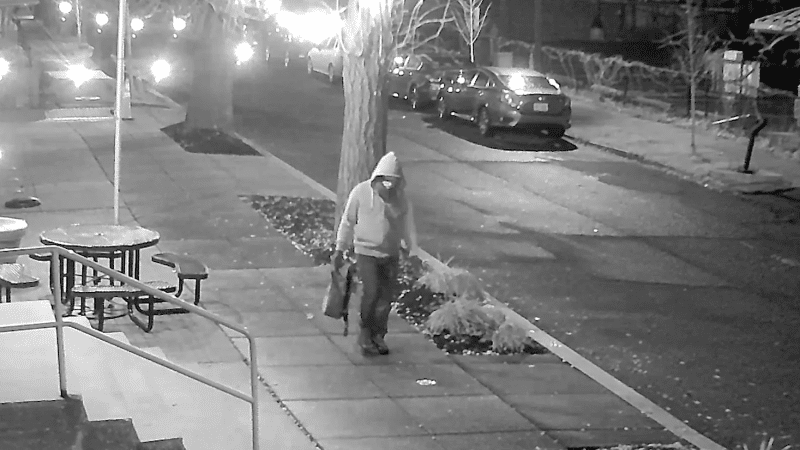FBI surveillance still of a hooded, masked suspect carrying a bag along a dark Capitol Hill sidewalk on January 5, 2021, in the January 6 pipe bomb case