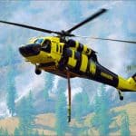 Yellow and black Sikorsky UH-60A Black Hawk firefighting helicopter carrying a water snorkel over smoke and forest at the Sinlahekin Fire in Washington