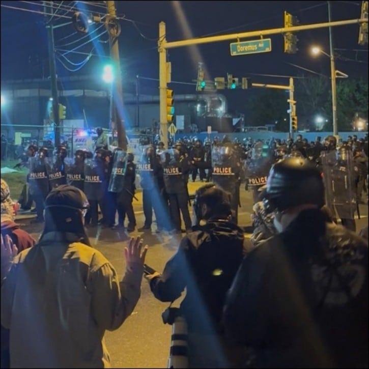 Riot police with shields face protesters at night outside Delaney Hall immigration detention center in Newark, New Jersey