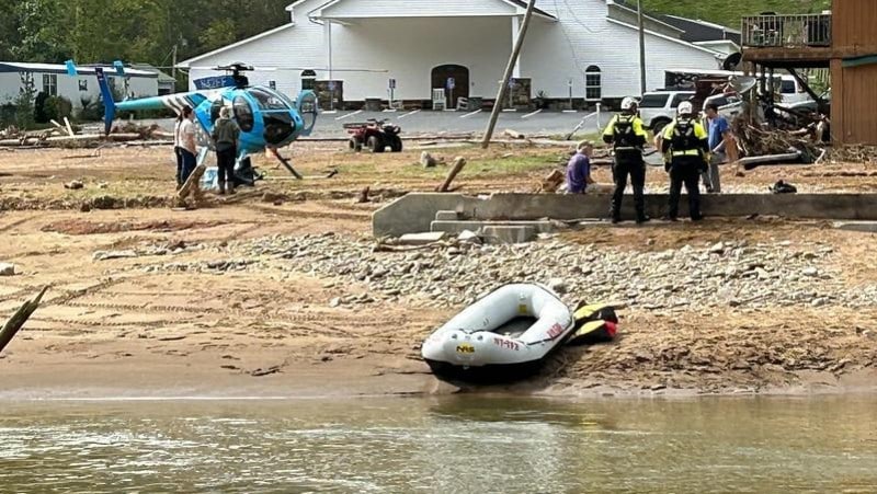 New York State search and rescue team with raft and helicopter on a flood-damaged riverbank near a church in western North Carolina after Hurricane Helene