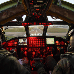 Two Air Force pilots in a red-lit B-52 cockpit approach the runway at RAF Fairford, England.