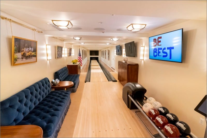 White House bowling alley after its 2019 renovation, with a single lane, tufted blue sofas and a Be Best sign on the wall screen