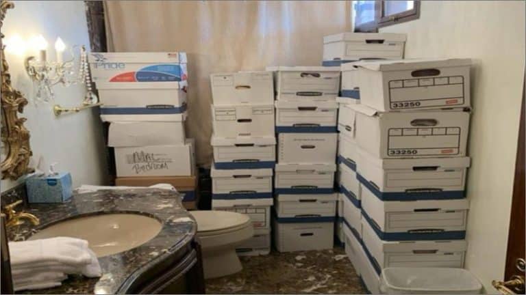 Stacks of white file boxes piled beside a toilet and marble sink in a gilded Mar-a-Lago bathroom