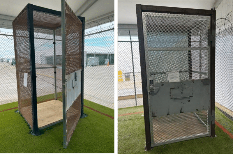 Empty 18-square-foot metal mesh cage on artificial turf inside a fenced yard at the Alligator Alcatraz detention site in Florida