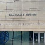 Donald Trump's name in metal letters above the United States Institute of Peace sign on the building's stone facade