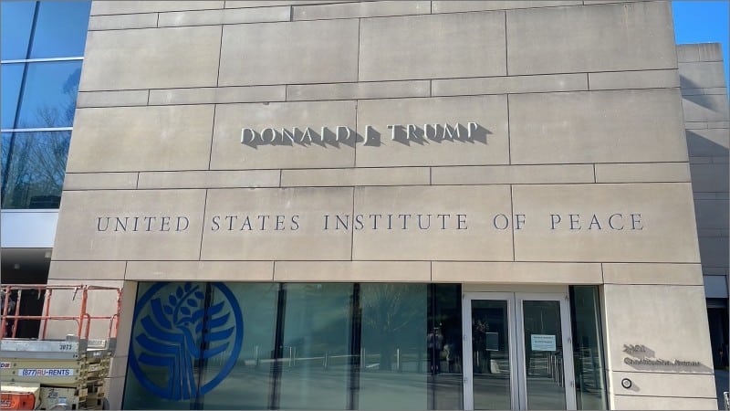 Donald Trump's name in metal letters above the United States Institute of Peace sign on the building's stone facade