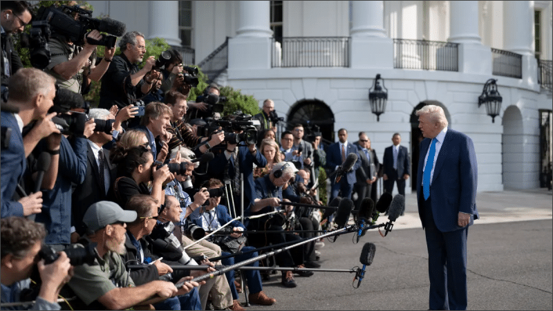 Donald Trump surrounded by press pool reporters, cameras and microphones outside the White House