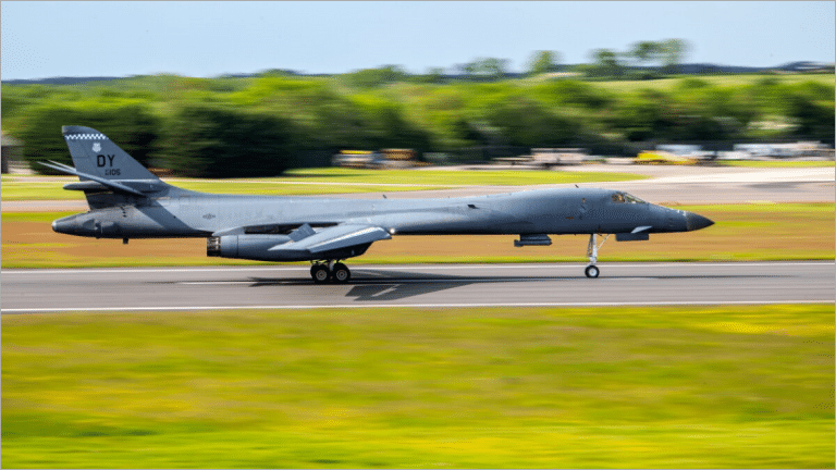 US Air Force B-1B Lancer bomber with a DY tail code rolling down the runway at RAF Fairford in England, green fields and trees behind it
