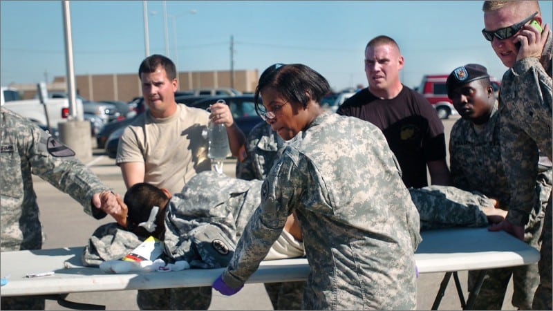 Soldiers and first responders carry a wounded US soldier on a table toward an ambulance in a Fort Hood parking lot after the 2009 shooting.