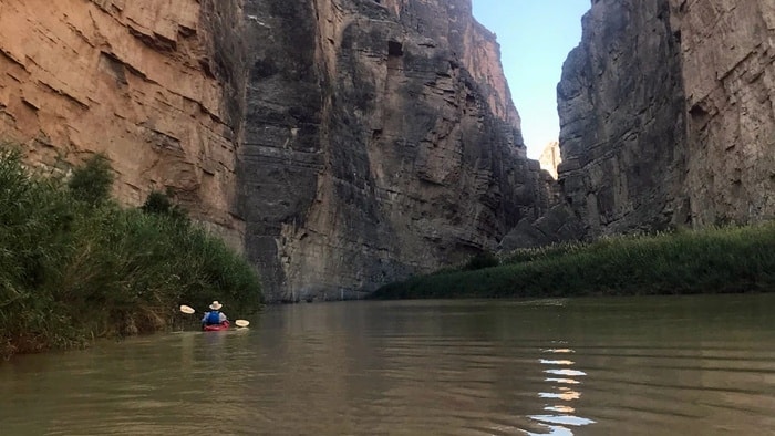 Kayaker paddling the Rio Grande between towering limestone cliffs of Santa Elena Canyon in Big Bend National Park, Texas